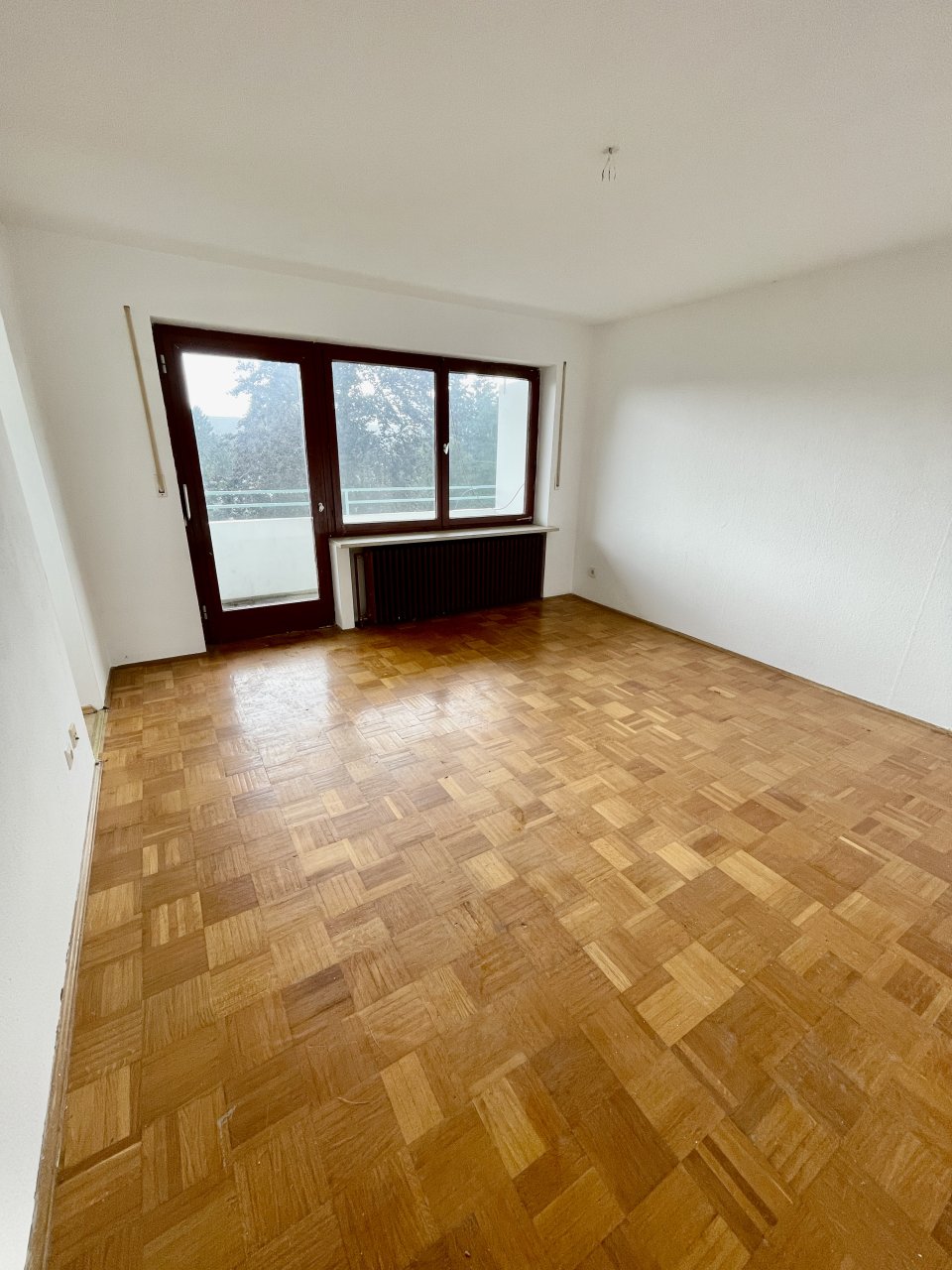 Wohnraum mit Parkett und Zugang zum Balkon